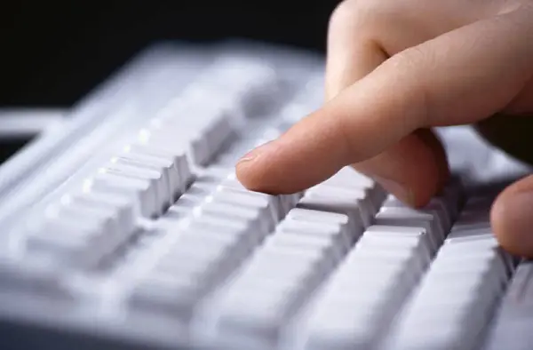 Mão digitando no teclado do computador era da informação
