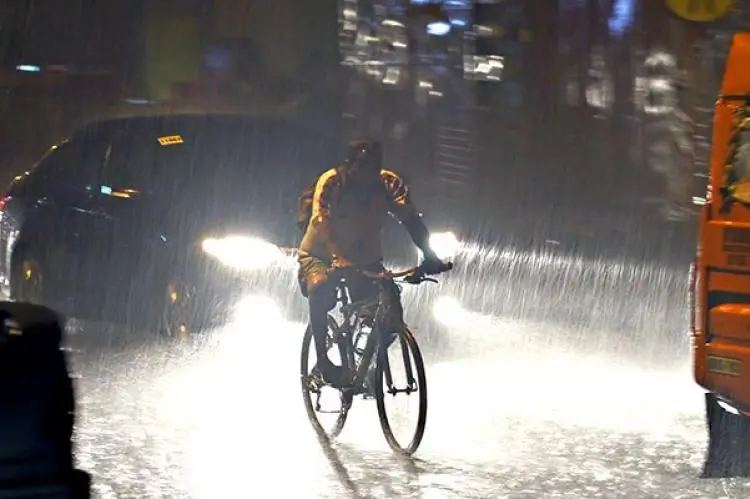 Homen de bicicleta na chuva de noite