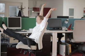Moça se espreguiça no ambiente de trabalho