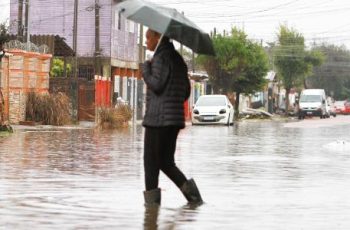 Homem usa galocha para atravessar enchente no bairro Mathias Velho, em Canoas, na região metropolitana de Porto Alegre
