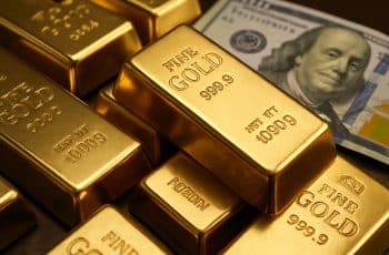 Barras de ouro empilhadas ao lado de cédula de dólar, representando a valorização do ouro em 2025.