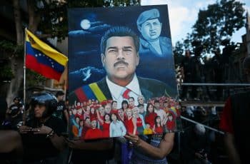 A woman shows a painting depicting ousted Venezuela's President Nicolas Maduro and former President Hugo Chavez (1999-2013) during a demonstration by supporters in Caracas on January 4, 2026, a day after he was captured in a US strike. Nicolas Maduro's congressman son called on January 4, 2026, for Venezuelans to take to the streets following his father's ouster by US forces and transfer to a New York jail. (Photo by Juan BARRETO / AFP)