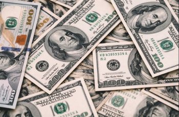Imagem mostra notas de dólar americano em destaque, representando a variação da moeda no mercado financeiro