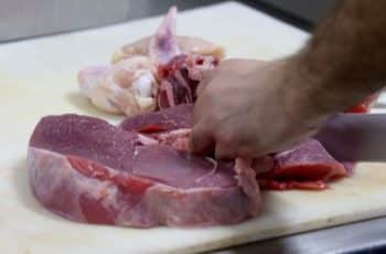 Mão cortando um pedaço de carne. Imagem ilustrativa para matéria sobre o preço do boi gordo que aumentou